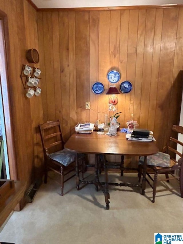 carpeted dining space with wood walls