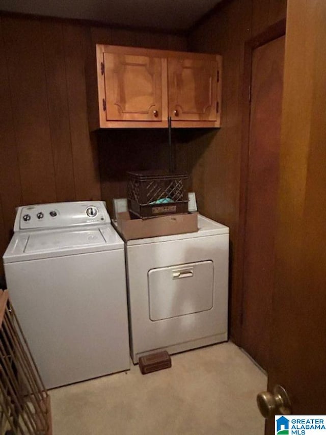 washroom featuring cabinets, separate washer and dryer, wooden walls, and light colored carpet