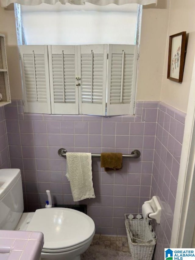 bathroom featuring toilet and tile walls