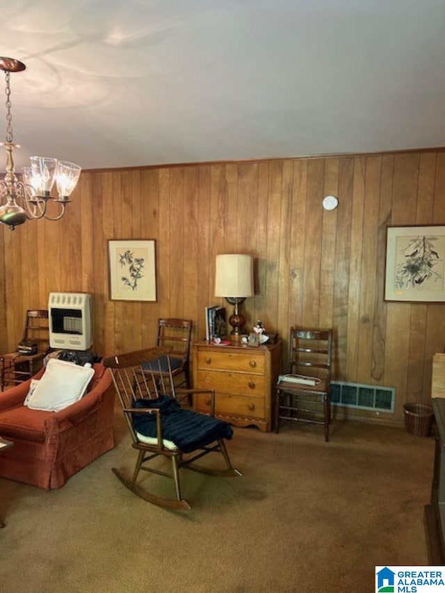 living area featuring a notable chandelier, carpet floors, wooden walls, and heating unit