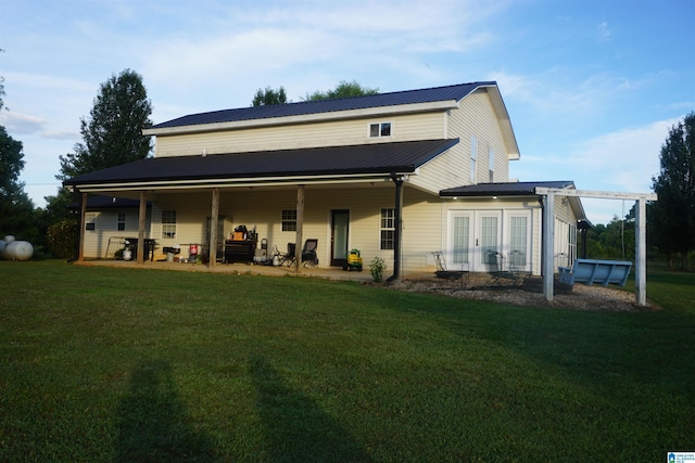 rear view of house with a yard, a patio, and a swimming pool