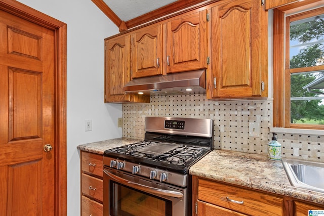 kitchen featuring backsplash, light stone countertops, ornamental molding, extractor fan, and stainless steel range with gas stovetop