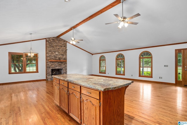 kitchen with a center island, a stone fireplace, light hardwood / wood-style flooring, lofted ceiling with beams, and ceiling fan with notable chandelier