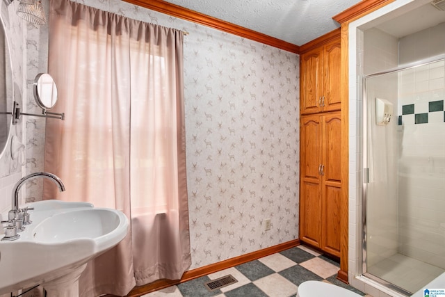 bathroom featuring a textured ceiling, an enclosed shower, crown molding, and sink