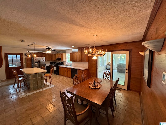 dining room with wooden walls, a textured ceiling, and plenty of natural light