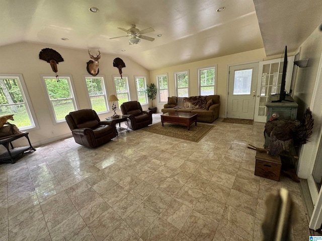 living room with a wood stove, vaulted ceiling, and ceiling fan