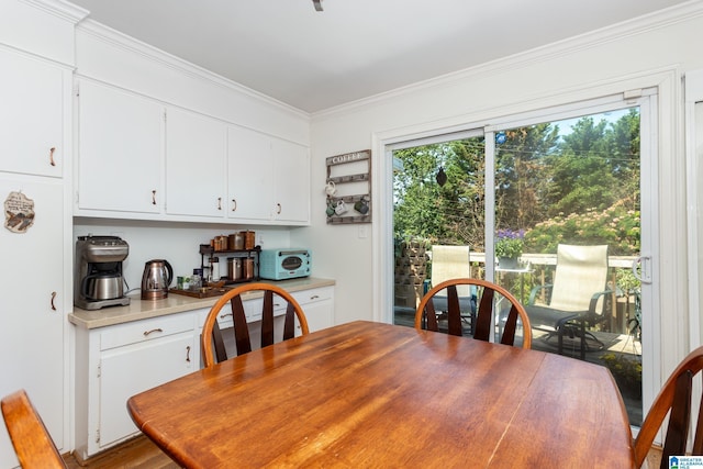 dining space with crown molding and light wood-type flooring