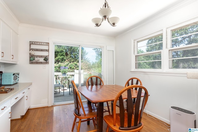 dining area featuring light hardwood / wood-style floors, crown molding, and a notable chandelier