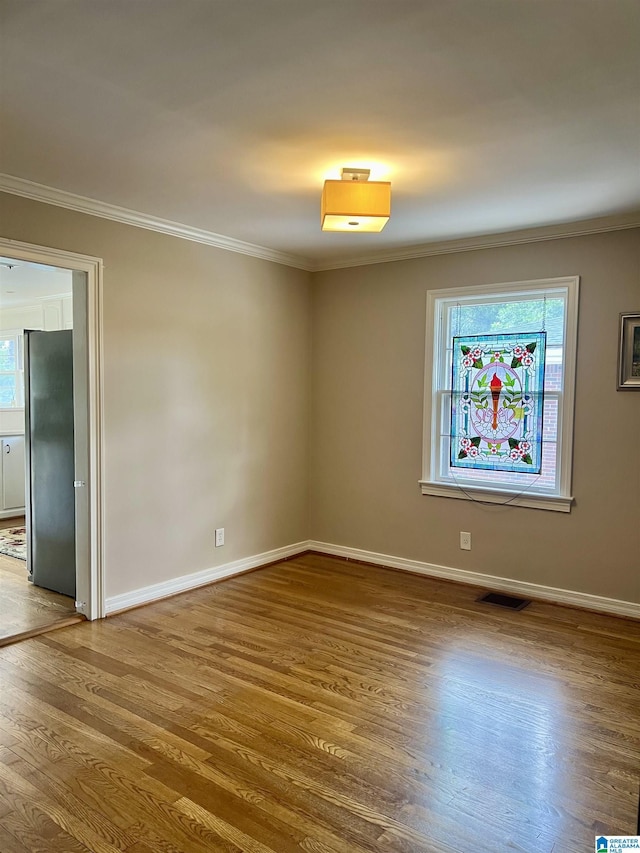 spare room with hardwood / wood-style flooring, plenty of natural light, and crown molding