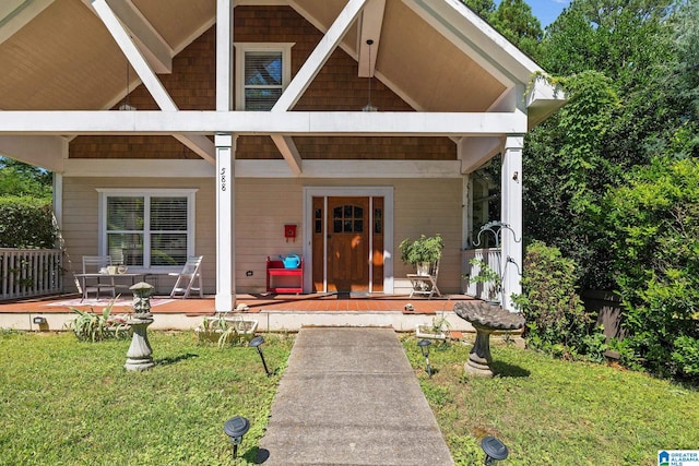 view of exterior entry with covered porch and a lawn