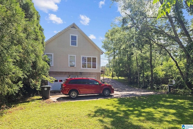 view of side of property with a lawn, a garage, and driveway