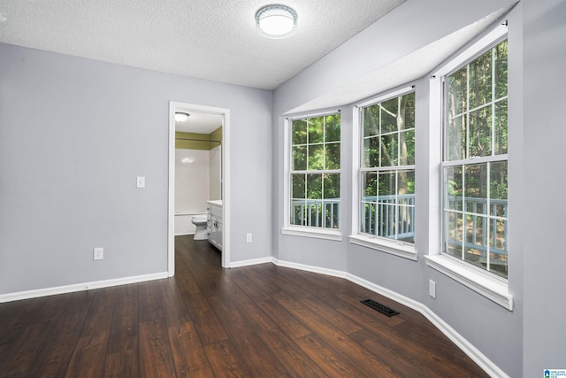 unfurnished room with dark wood-type flooring and a textured ceiling