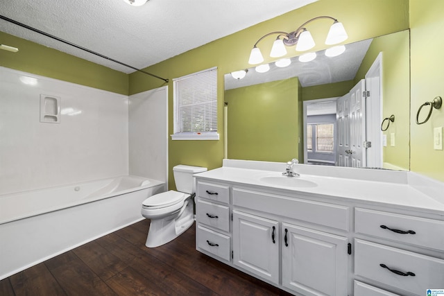 full bathroom with tub / shower combination, hardwood / wood-style floors, a textured ceiling, toilet, and vanity