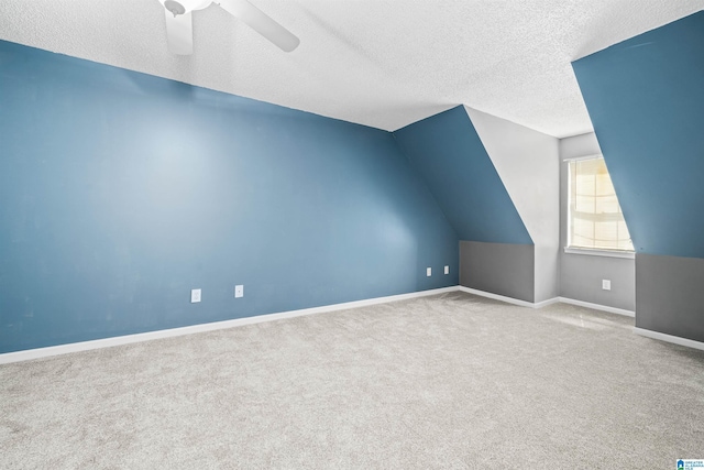 additional living space featuring carpet flooring, lofted ceiling, ceiling fan, and a textured ceiling