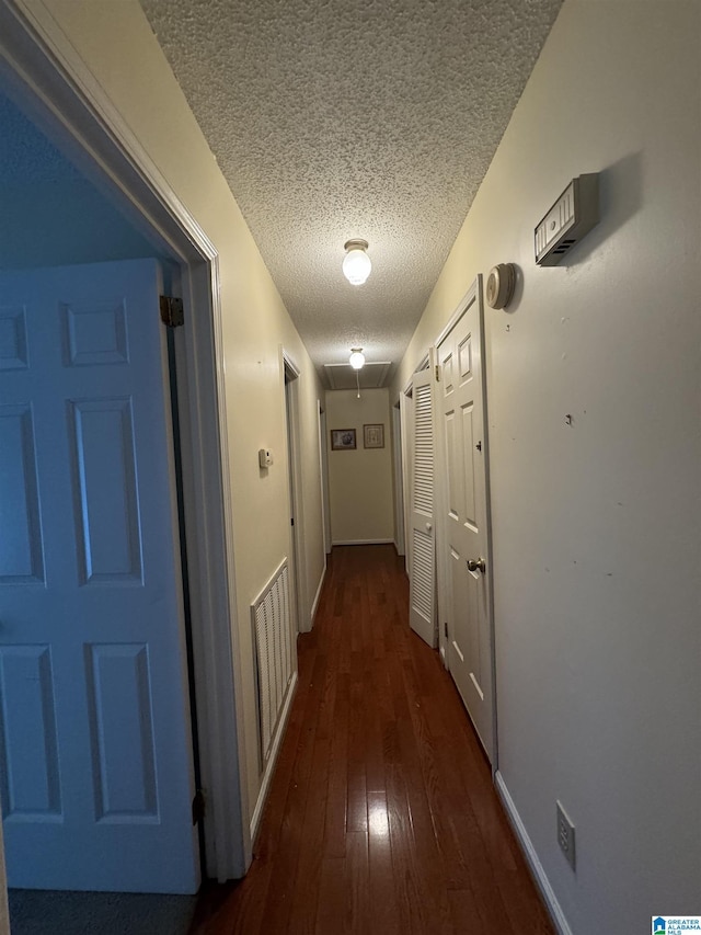 corridor featuring a textured ceiling and dark wood-type flooring