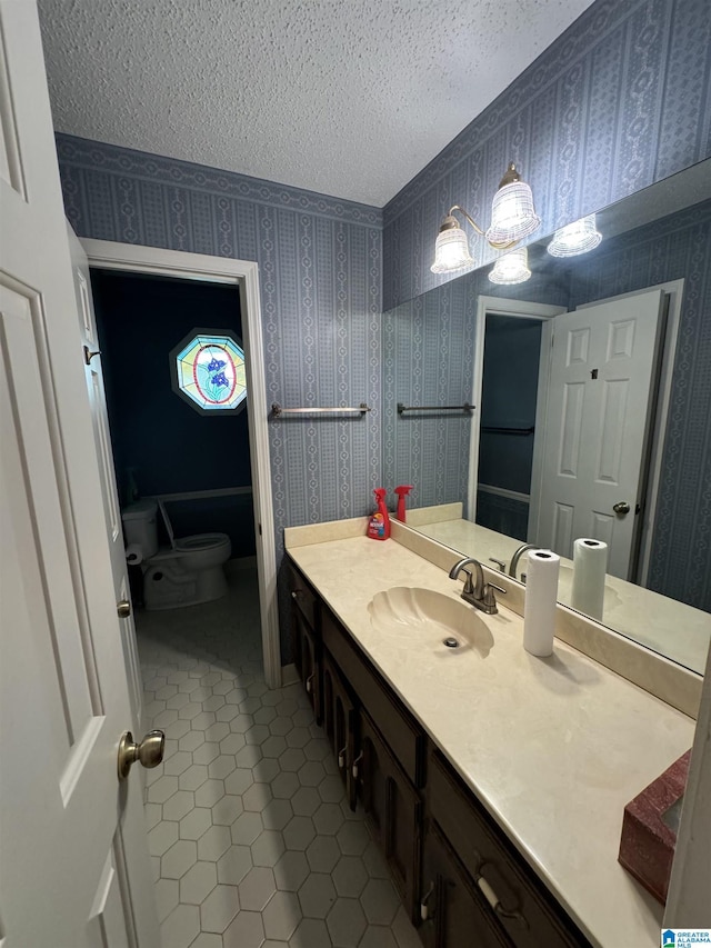 bathroom with toilet, tile patterned flooring, vanity, and a textured ceiling