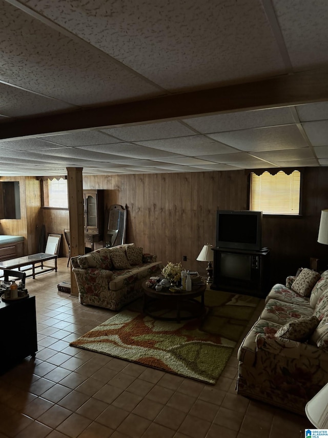 tiled living room featuring a paneled ceiling and wooden walls