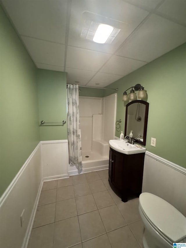 bathroom with tile patterned flooring, toilet, a paneled ceiling, vanity, and curtained shower