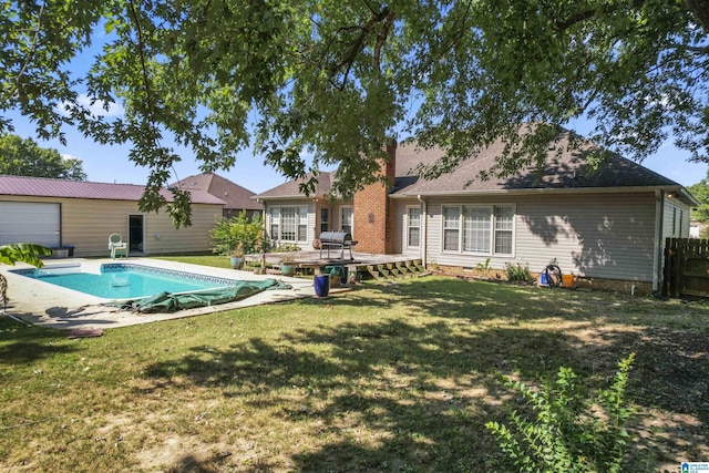 rear view of property featuring a covered pool, fence, and a yard