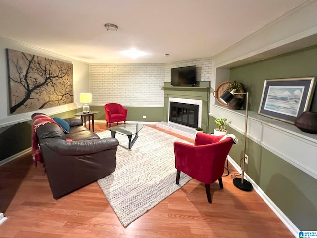 living room featuring a large fireplace, wood-type flooring, and brick wall