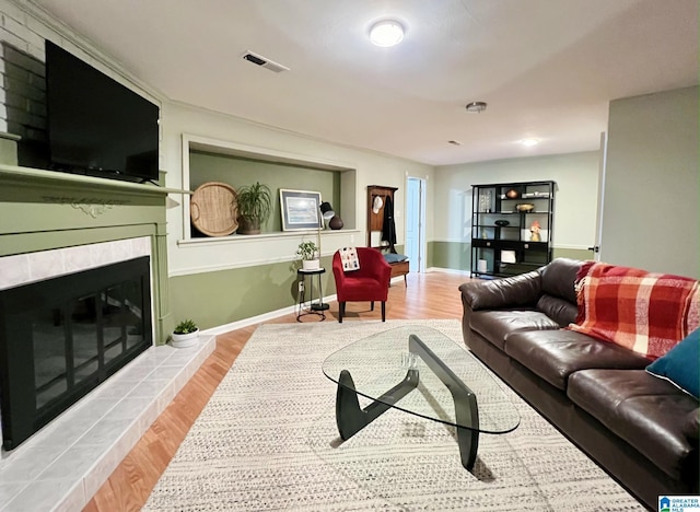 living room featuring a tiled fireplace and hardwood / wood-style floors