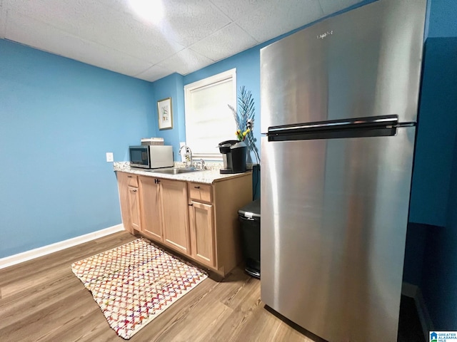 kitchen featuring light brown cabinetry, sink, stainless steel appliances, and light wood-type flooring