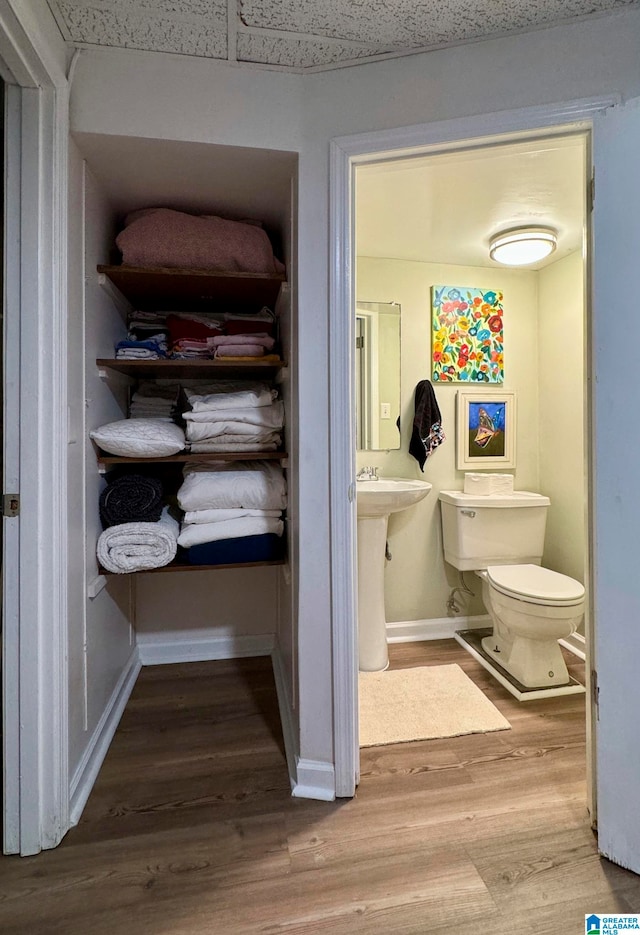 bathroom featuring a drop ceiling, wood-type flooring, and toilet