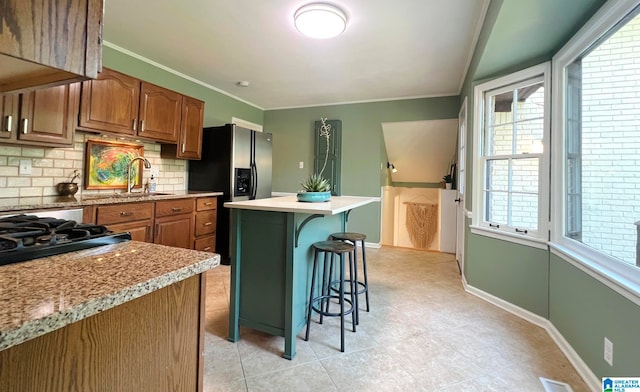 kitchen with a breakfast bar, a center island, tasteful backsplash, a healthy amount of sunlight, and stainless steel fridge with ice dispenser