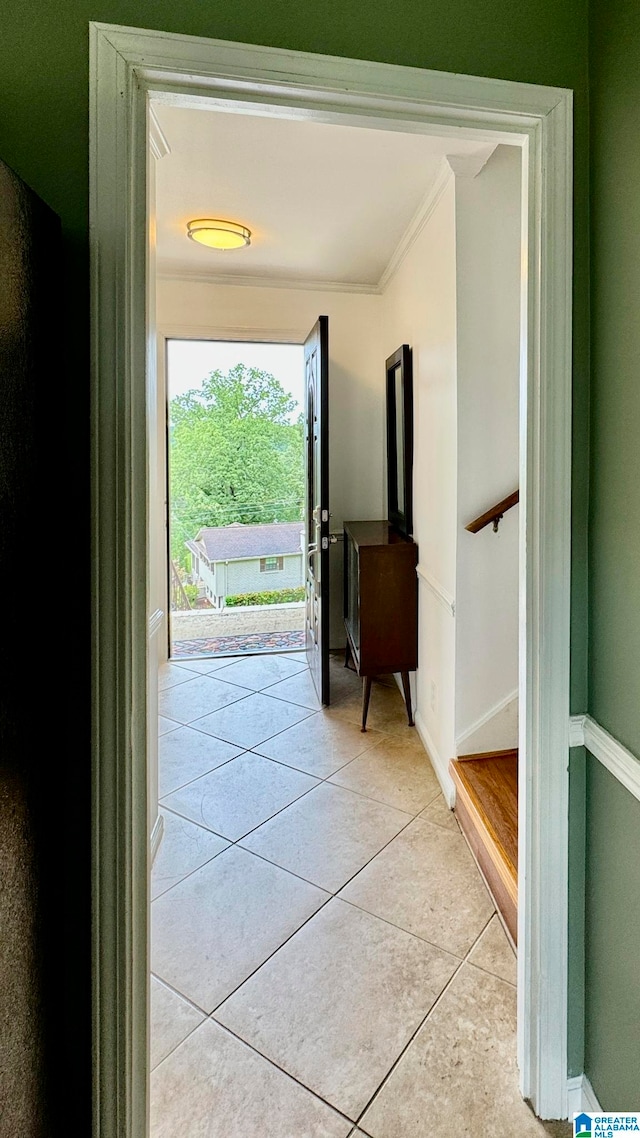 entryway with crown molding and light tile patterned flooring