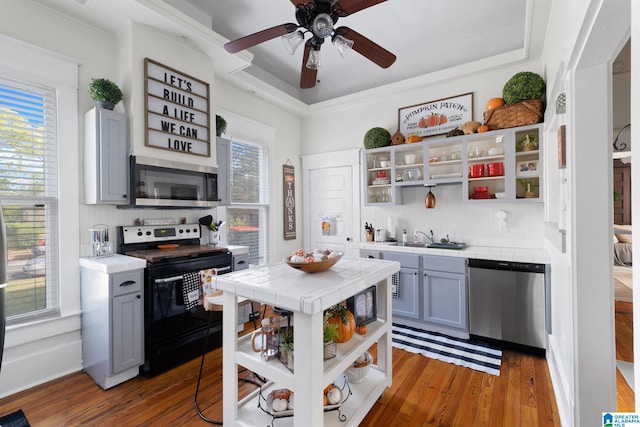 kitchen with sink, gray cabinetry, backsplash, hardwood / wood-style flooring, and stainless steel appliances