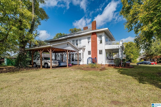 back of property featuring a carport, a balcony, and a yard