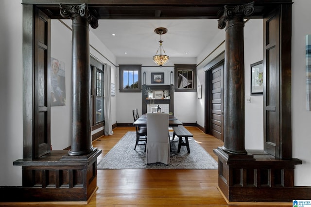 dining area featuring decorative columns and light hardwood / wood-style floors