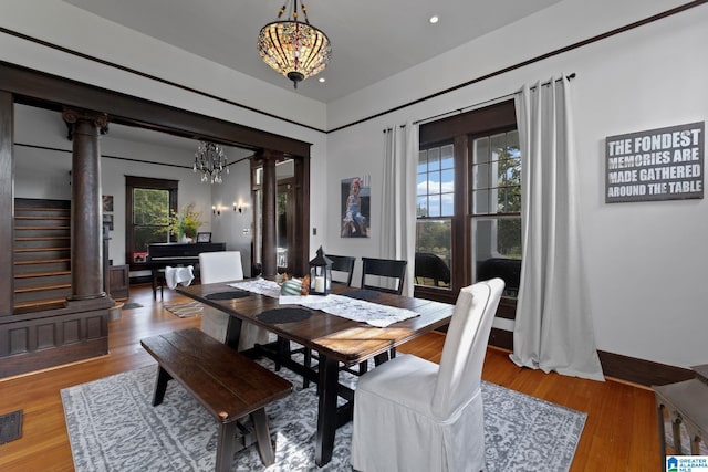 dining room featuring an inviting chandelier, hardwood / wood-style floors, decorative columns, and a healthy amount of sunlight