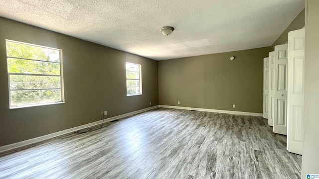 spare room featuring a textured ceiling and light wood-type flooring