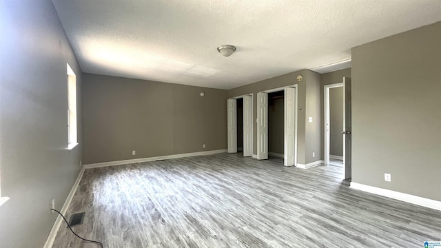 spare room with a textured ceiling and light wood-type flooring