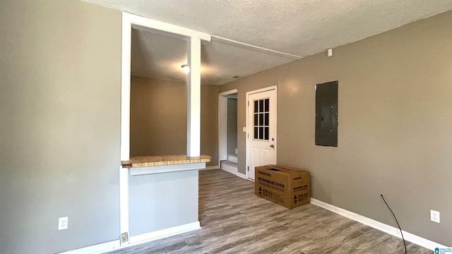 spare room with electric panel, wood-type flooring, and a textured ceiling