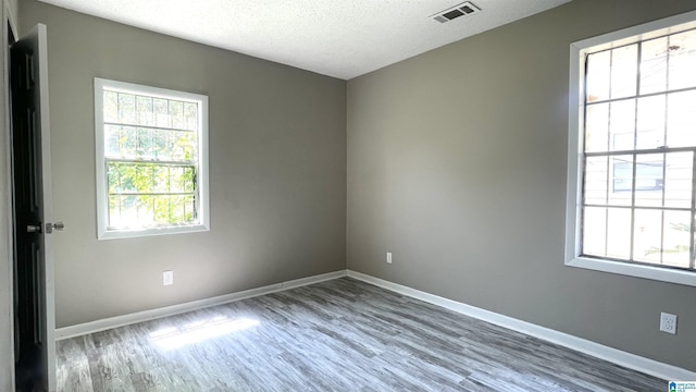 unfurnished room with hardwood / wood-style floors and a textured ceiling