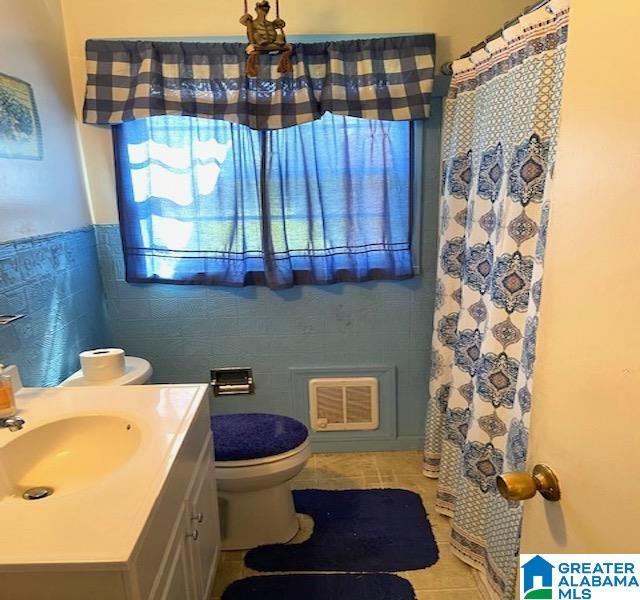 bathroom featuring tile patterned floors, a shower with curtain, vanity, tile walls, and toilet