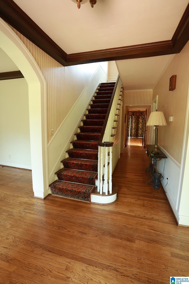 stairway with hardwood / wood-style flooring and crown molding