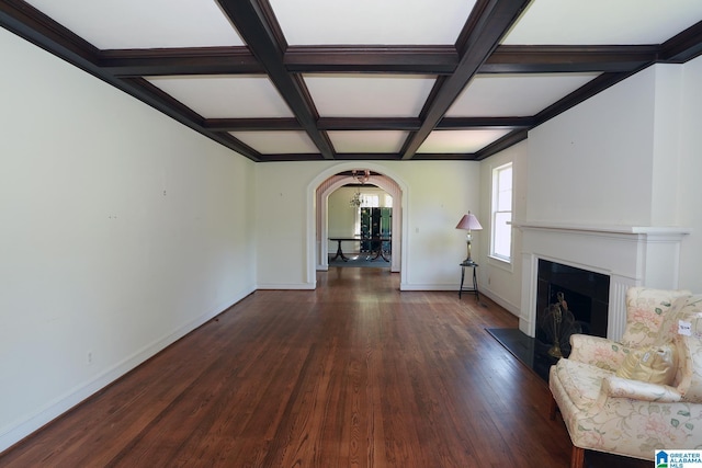 unfurnished living room featuring beamed ceiling, a notable chandelier, dark wood-type flooring, and coffered ceiling