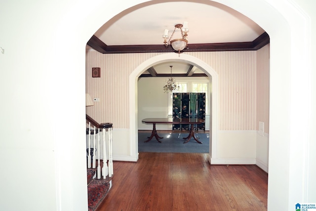 corridor with crown molding, dark wood-type flooring, and an inviting chandelier