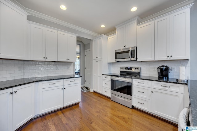 kitchen with white cabinets, light wood-type flooring, backsplash, and appliances with stainless steel finishes