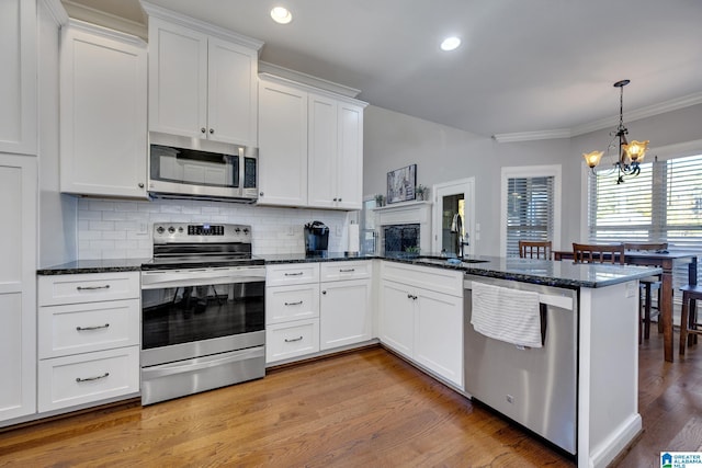 kitchen featuring sink, stainless steel appliances, backsplash, kitchen peninsula, and white cabinets