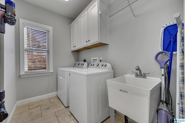 washroom featuring washing machine and clothes dryer, sink, light tile patterned floors, and cabinets