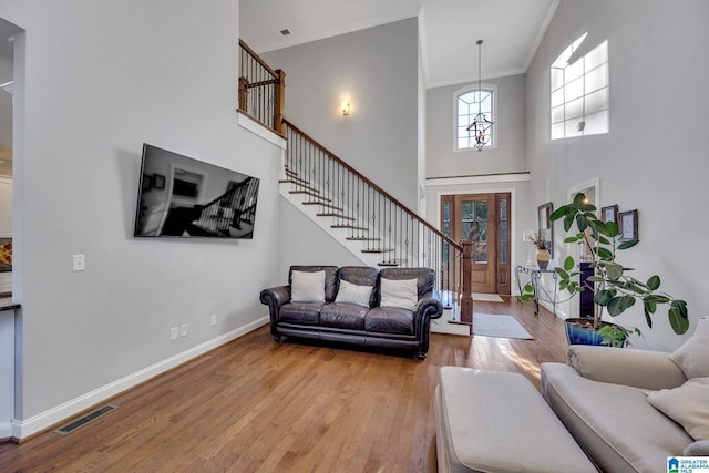 living room with light wood-type flooring, ornamental molding, and a high ceiling