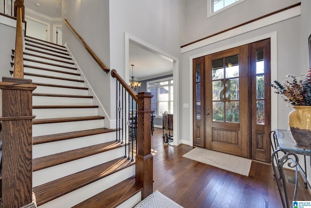 foyer featuring dark hardwood / wood-style floors, crown molding, and a notable chandelier