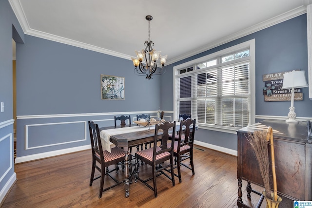 dining space featuring dark wood-type flooring, crown molding, and a notable chandelier