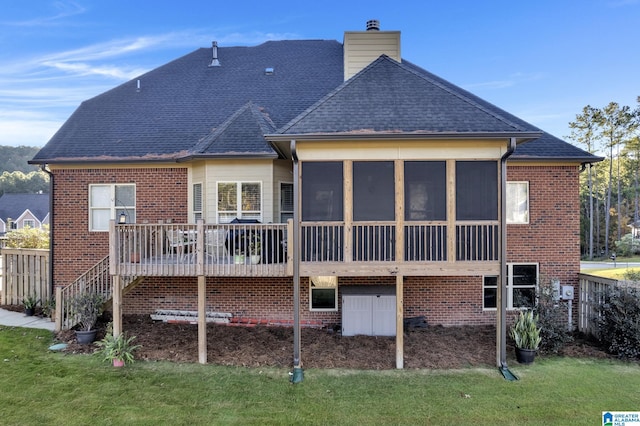 rear view of house with a sunroom, a deck, and a yard