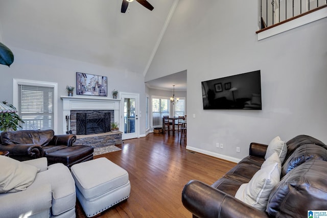 living room featuring high vaulted ceiling, ceiling fan with notable chandelier, ornamental molding, a fireplace, and dark hardwood / wood-style flooring