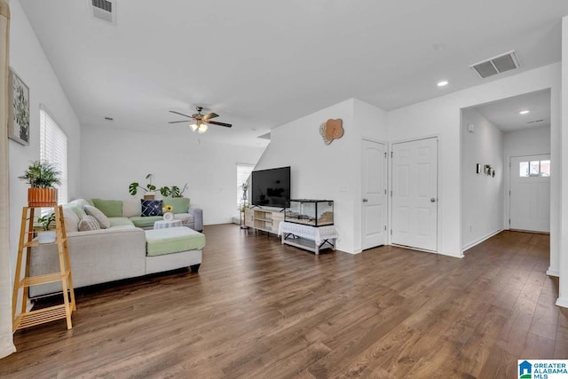 living room featuring dark wood-type flooring, ceiling fan, and a healthy amount of sunlight